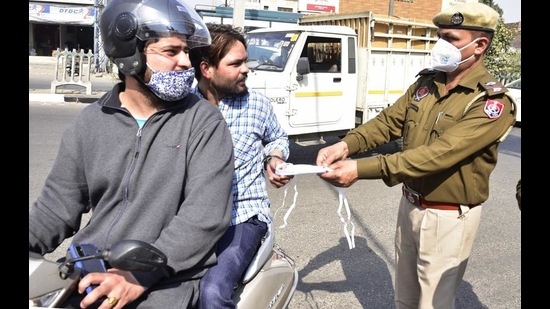 Ludhiana police personnel distrusting masks to the commuters on Tuesday. (Gurpreet Singh/HT) Ludhiana police personnel distrusting masks to the commuters on Tuesday. (Gurpreet Singh/HT)