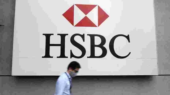 A man wearing a protective mask walks past a logo of HSBC at its headquarters.(Reuters)