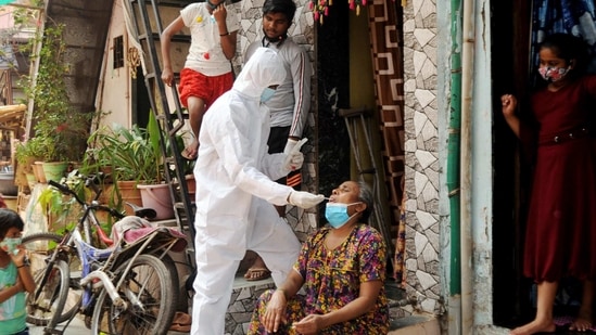 A BMC health worker wearing protective gear takes a swab sample of a woman for the Covid-19 test at Dharavi, in Mumbai on Tuesday. (ANI Photo) A BMC health worker wearing protective gear takes a swab sample of a woman for the Covid-19 test at Dharavi, in Mumbai on Tuesday. (ANI Photo)