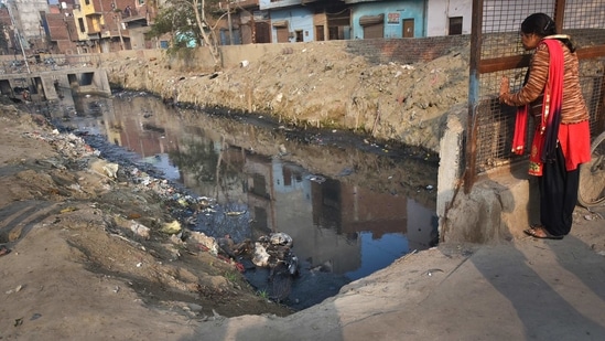 A passer-by looks at an abandoned body lying in a nullah at Brahampuri in New Delhi, India, on Thursday, February 27, 2020. (Amal KS/ HT Archive)