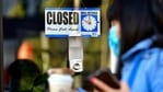 A pedestrian wearing her facemask and holding a cup of coffee walks past a closed sign hanging on the door of a small business in Los Angeles, California.(AFP) A pedestrian wearing her facemask and holding a cup of coffee walks past a closed sign hanging on the door of a small business in Los Angeles, California.(AFP)
