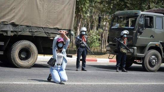 A demonstrator gestures as riot police officers stand guard during a rally against the military coup at the University of Yangon on February 25.(REUTERS)