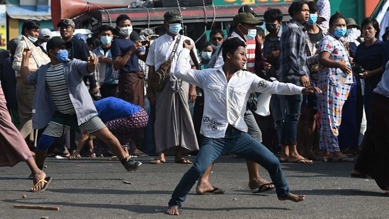 Pro-military supporters throw projectiles at residents in Yangon on February 25. Clashes Broke out near Yangon Central station's railway compound by noon on February 25. Military supporters -- some carrying pipes, knives and slingshots -- turned on the booing residents, witnesses told AFP.(Sai Aung Main / AFP)