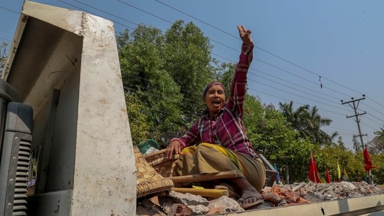 A woman travelling in the back of a truck greets anti-coup protesters with the three-fingered salute in Mandalay on February 25.(AP)
