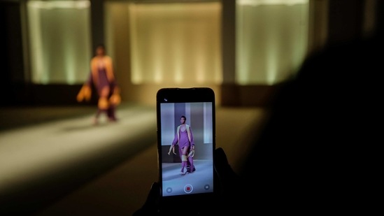 A model seen through the screen of a smartphone wears a creation designed by fashion designer Gisele Claudia, as part of the Black Lives Matter Fall/Winter 2021/22 collective fashion show, presented in Milan, Italy, Wednesday, Feb. 17, 2021. 2021.(AP)