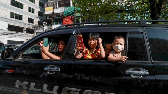Children peep out of a car and react to anti-coup protesters with clenched fists in Yangon on February 25.(AP)