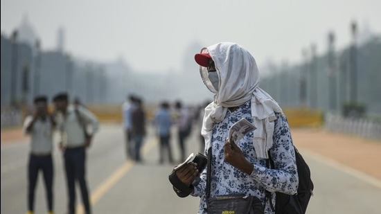 A photographer has a cloth wrapped around his head to beat the heat at India Gate in New Delhi. (HT file)