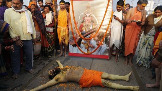 A Hindu Holy man lies in front of an image of Hindu Goddess of learning Saraswati, at Sangam, the sacred confluence of the rivers Ganga, Yamuna and the mythical Saraswati, during Magh Mela festival, in Prayagraj, India Tuesday, Feb. 16, 2021.(AP)