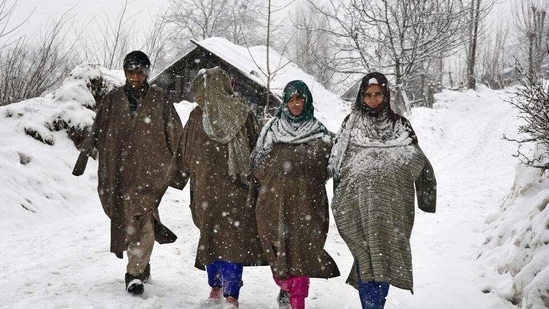 People walk on a snow-covered road at Ahlan village in South Kashmir. (File photo)