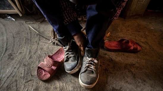 Imradul Ali, 10, puts on a pair of shoes which he salvaged from a landfill before going to school from his rented room on the outskirts of Guwahati, India, Thursday, Feb. 4, 2021. (AP)