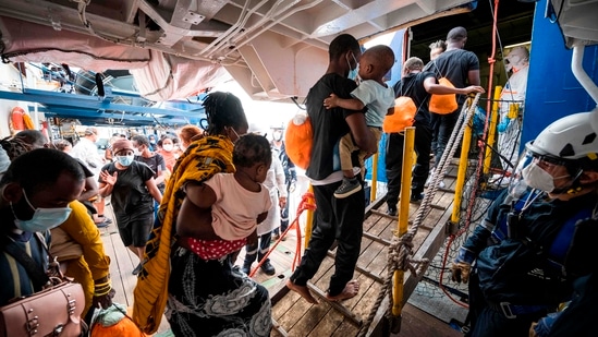 (FILES) In this file photo taken on September 02, 2020 rescued migrants are greeted by crew members of the Sea-Watch 4 rescue boat and Doctors without Borders (Medecins Sans Frontieres, MSF) as they leave the Sea-Watch 4 to board a ferry on which some 350 migrants will be under quarantine, off the coast of Palermo, Sicily, Italy. - The UN voiced alarm on January 28, 2021 at increasingly frequent pushbacks and expulsions of refugees at Europe's borders, warning that the very idea of asylum itself was under attack on the continent. (Photo by Thomas Lohnes / AFP)(AFP)