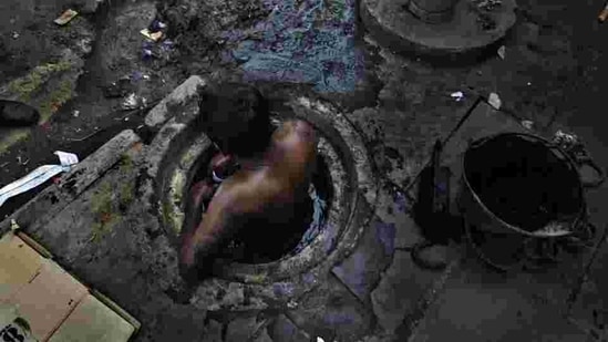 Municipal worker attempts to unblock a sewer overflowing with human excreta in New Delhi. Although a law bans manual scavenging - the manual removal of human excreta from 'dry toilets' - the practice is widespread across cities and towns in India.(Photo: Raj K Raj / Hindustan Times)