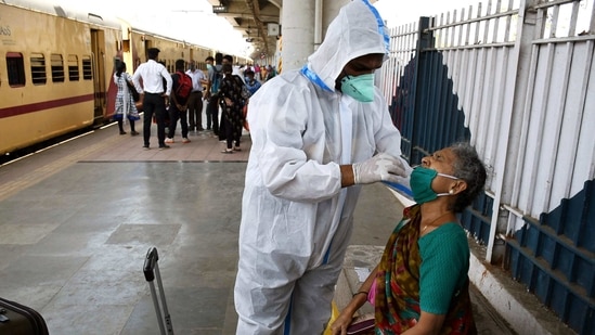 A health worker wearing a PPE kit collects a swab sample of an old lady for the Covid-19 test at Dadar railway station. (ANI Photo)