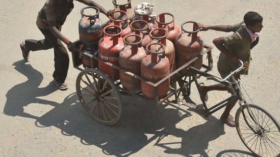 Delivery persons transporting LPG gas cylinders in a rickshaw cart in Patna (Photo by Parwaz Khan / Hindustan Times)