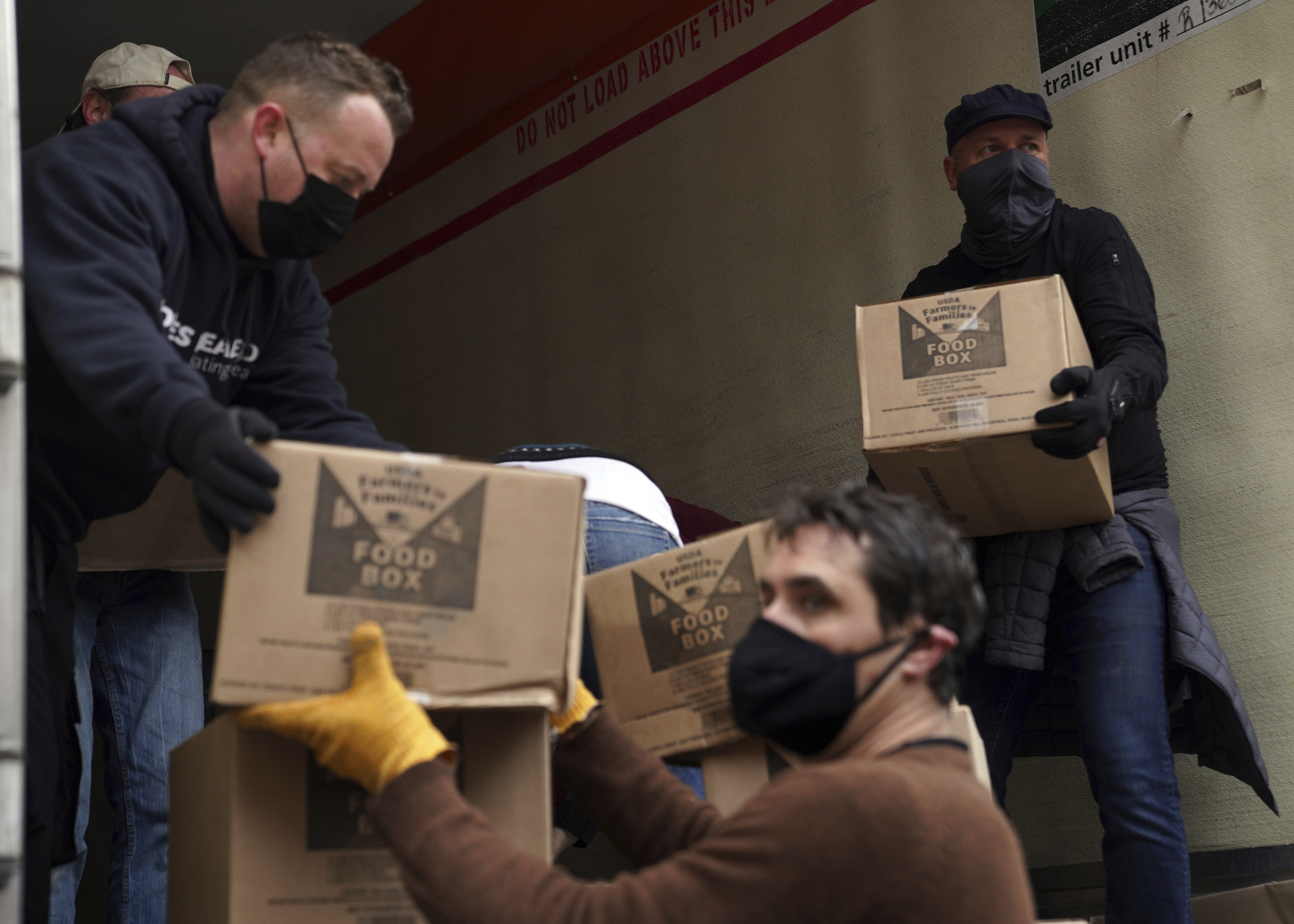 Volunteers unload boxes of food from a truck for a distribution program.(AP) Volunteers unload boxes of food from a truck for a distribution program.(AP)