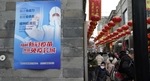 Residents wearing masks to protect from the coronavirus visits a popular retail street near a poster advocating for vaccination to fight the coronavirus on the third day of the Chinese Lunar New Year in Beijing. (AP Photo) Residents wearing masks to protect from the coronavirus visits a popular retail street near a poster advocating for vaccination to fight the coronavirus on the third day of the Chinese Lunar New Year in Beijing. (AP Photo)