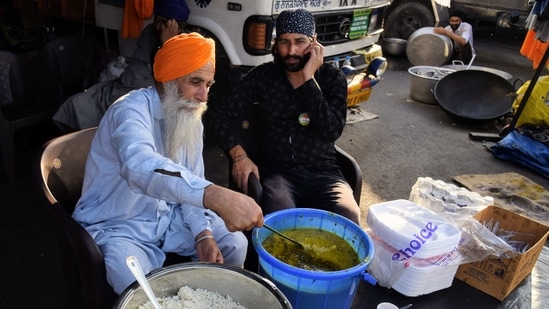 Volunteers sit to distribute langar at the site during an ongoing farmers' protest against the three farm laws at the Ghazipur border, in Delhi on Thursday. (ANI Photo) Volunteers sit to distribute langar at the site during an ongoing farmers' protest against the three farm laws at the Ghazipur border, in Delhi on Thursday. (ANI Photo)