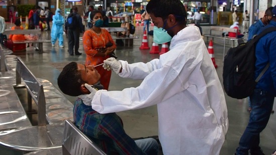 A health worker wearing protective gear takes a nasal swab sample of inbound travellers for Covid-19 coronavirus tests at CSMT railway station, in Mumbai. (Bhushan Koyande / HT Photo)