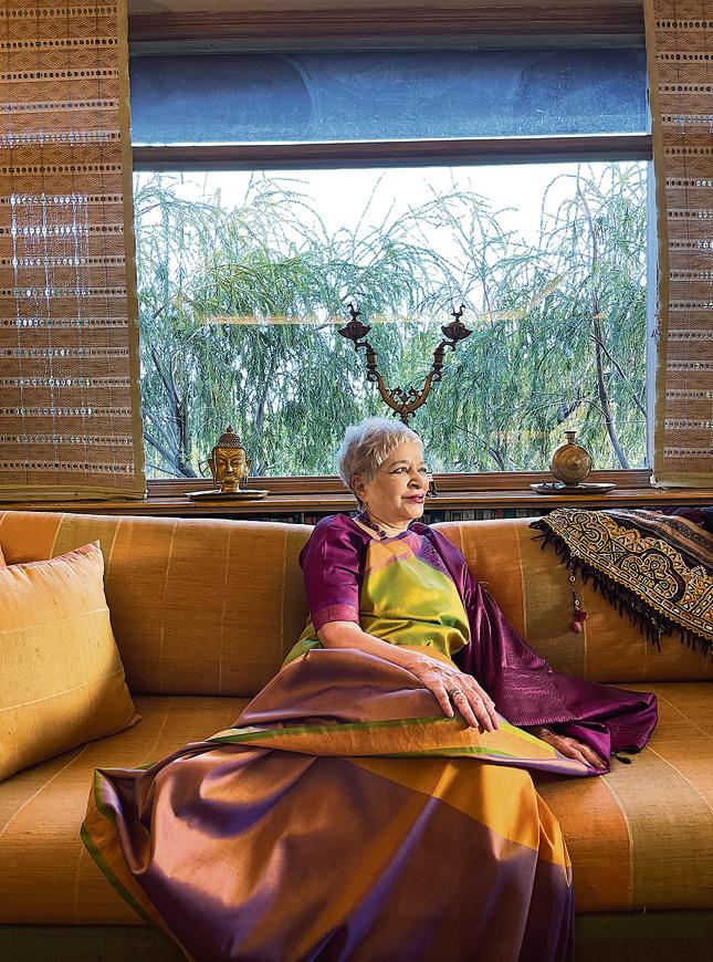 Behind her sofa is a huge glass window through which all you see are sky, clouds and trees. Behind her sofa is a huge glass window through which all you see are sky, clouds and trees.