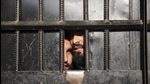 Uma foto de arquivo de prisioneiros do Taleban olhando pela porta de uma prisão após um ataque na cidade de Jalalabad, no Afeganistão.  (AP)