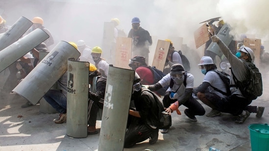 Protesters take cover as they clash with riot police officers during a protest against the military coup in Yangon, Myanmar.(Reuters)