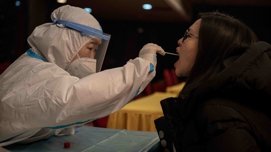 A health worker (L) takes a mouth swab sample from a journalist for a Covid-19 nucleic acid test.(AFP) A health worker (L) takes a mouth swab sample from a journalist for a Covid-19 nucleic acid test.(AFP)