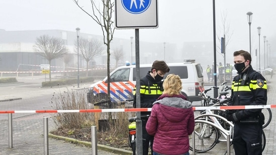 Police officers speak with a pedestrian as they close off a street after an explosion occurred near a Covid-19 test centre, shattering windows but causing no apparent injuries, in Bovenkarspel, the Netherlands.(AFP)
