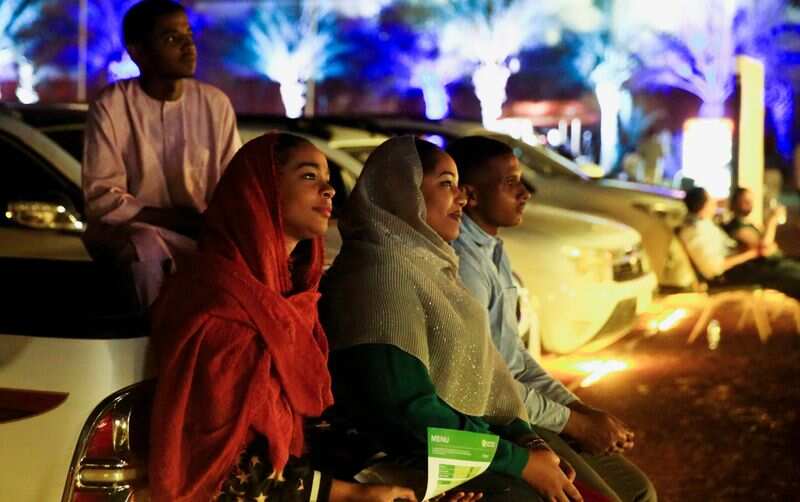 People sit on a car as they watch a screening of the Sudanese European Film Festival at an outdoor, drive-through cinema for visitors, adhering to coronavirus disease (COVID-19) restrictions, in Khartoum, Sudan February 28, 2021. (REUTERS)