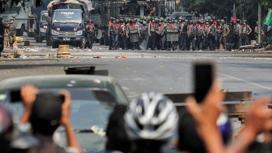 Police seen at the distance as demonstrators use mobile phones to film during an anti-coup protest in Mandalay, Myanmar on March 3. Police again used force to try to disperse the crowds, AP reported citing video footage on social media accounts.(REUTERS)