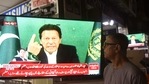 Um espectador ouve o primeiro-ministro do Paquistão, Imran Khan, falando à nação na televisão.  (AFP)