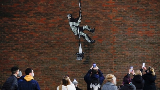 People take pictures of a suspected new mural by artist Banksy on a wall at HM Reading Prison in Reading, Britain, March 1, 2021(REUTERS)