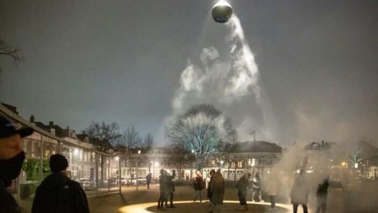 A group of actors dance in a ring of ultraviolet light projected onto a square in Rotterdam from a glowing black orb suspended above them.(Reuters) A group of actors dance in a ring of ultraviolet light projected onto a square in Rotterdam from a glowing black orb suspended above them.(Reuters)