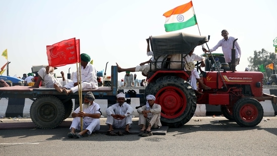 Farmers sitting near their tractor as they take part in a road blockade to mark the 100th day of the protest against the new farm laws on a highway near Kundli Border on Saturday. (ANI Photo)