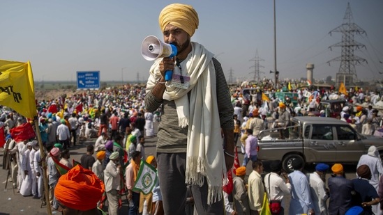 A farmer makes announcements standing on a truck while blocking a major highway to mark 100 days of the ongoing farmer protests, along Delhi-Haryana border on March 6. The farmers have remained undeterred even after violence erupted on January 26 during clashes with police that left one protester dead and hundreds injured.(Altaf Qadri/AP)