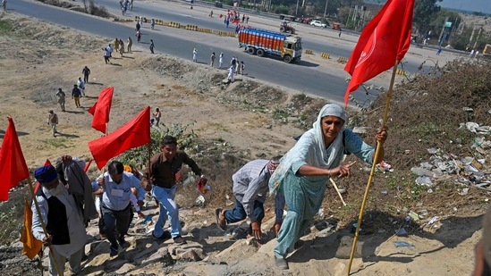 Protesters walk next to a national highway to block KMP Expressway during a call for a five-hour roadblock on March 6. Samyukta Kisan Morcha, or Joint Farmers’ Front, said the blockade would last five hours. “It is not our hobby to block roads, but the government is not listening to us. What can we do?” Satnam Singh, a member of the group told AP.(Prakash Singh/AFP)