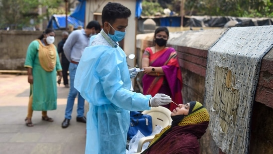 A health worker takes swab sample of a resident for Covid-19 testing in a housing society, amid a surge in coronavirus cases, at Nehru Nagar in Mumbai.(PTI)