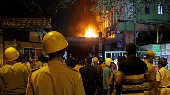 Firefighters and locals stand and watching fire after it broke out on the 13th floor of a multi-storeyed building and housing offices of the Railways, on Strand Road in Kolkata on Monday. (ANI Photo)
