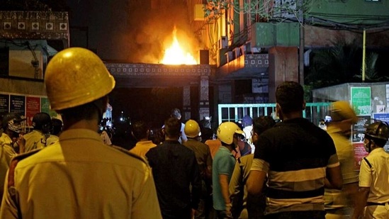 Firefighters and locals stand and watching fire after it broke out on the 13th floor of a multi-storeyed building and housing offices of the Railways, on Strand Road in Kolkata on Monday. (ANI Photo)