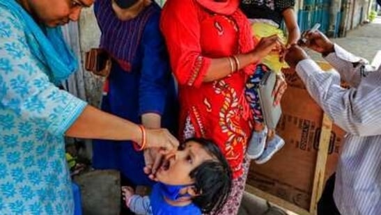 A health worker administers polio vaccine to a child as another marks a child on her finger.(AP)
