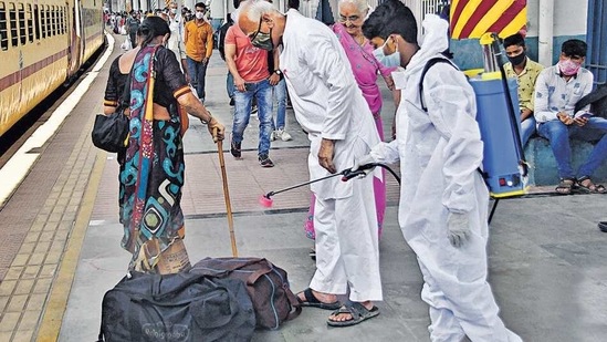 A health worker wearing PPE kit sanitises a luggage of a passenger at Dadar station in Mumbai. (Bhushan Koyande/ HT Photo)(HT_PRINT)