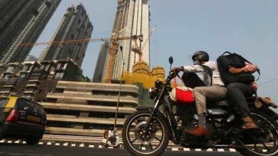 A man rides past buildings under construction in Mumbai, India.(AP)