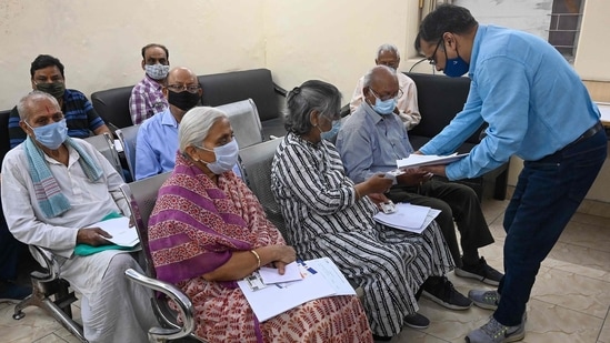 A medical worker examines the documents of an elderly who arrived to get a jab of Covid-19 coronavirus vaccine at vaccination centre in New Delhi. (AFP)