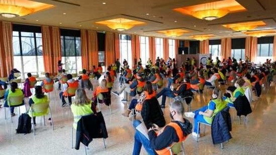 Wearing colored vests, volunteer workers sit socially distanced as they take part in a training session before a shift working at a mass vaccination clinic at Seattle University. (AP Photo ) Wearing colored vests, volunteer workers sit socially distanced as they take part in a training session before a shift working at a mass vaccination clinic at Seattle University. (AP Photo )