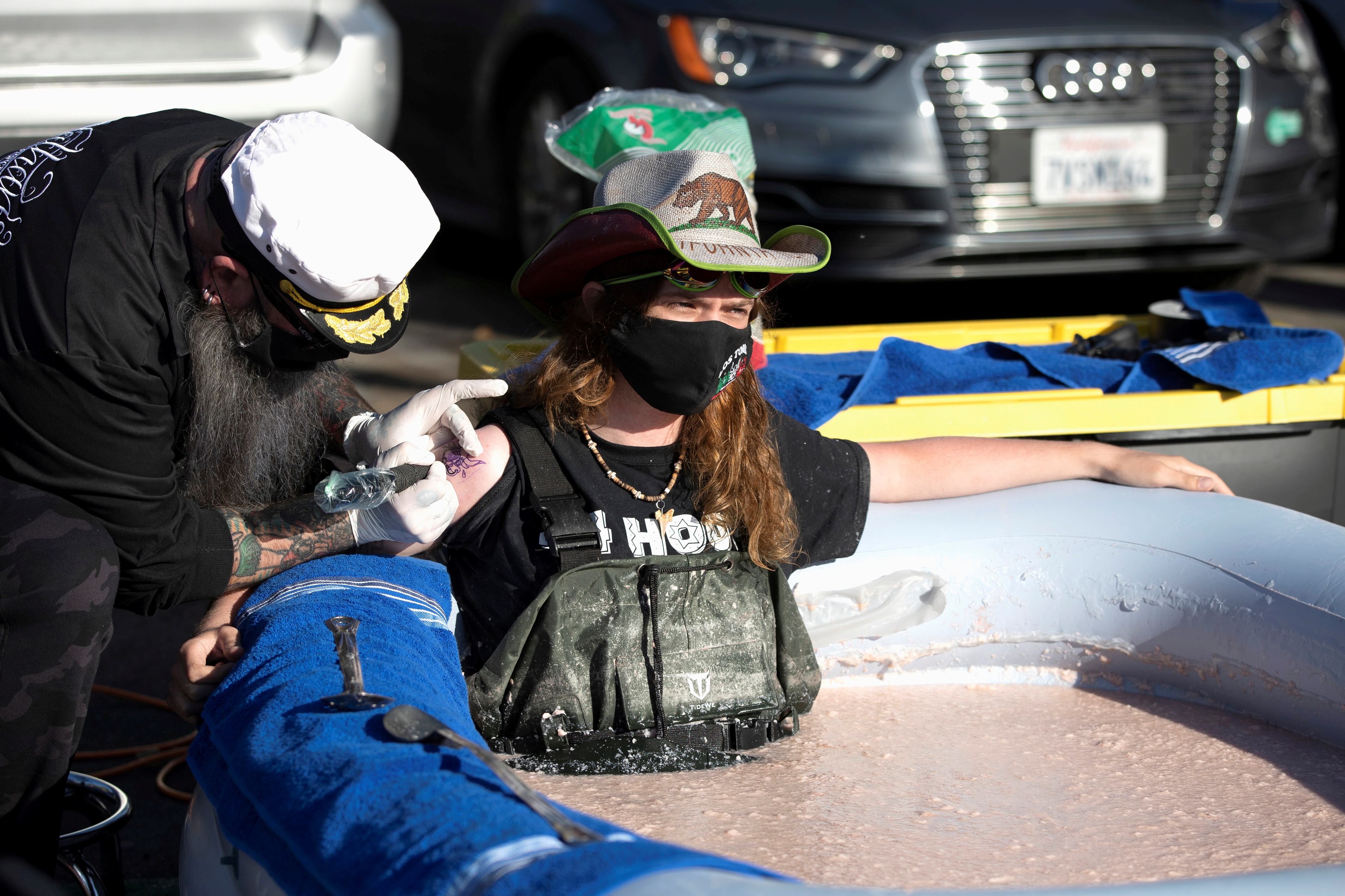 Stuntman Hunter Ray Barker gets a logo of the restaurant tattooed on his arm as he sits partially submerged in a bean dip tub. (REUTERS)
