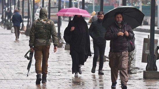 People walks along a sidewalk during a rainfall in Srinagar on March 10, 2021. (Photo by Tauseef Mustafa / AFP)(AFP) People walks along a sidewalk during a rainfall in Srinagar on March 10, 2021. (Photo by Tauseef Mustafa / AFP)(AFP)