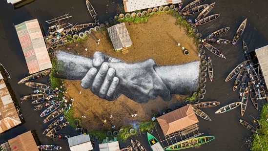 Ganvie: An aerial view shows a giant landart fresco by French-Swiss artist Saype, painted for the 10th step of his worldwide 'Beyond Walls' project in Ganvie, village on stilts, Benin, on Wednesday March 3, 2021. Five frescoes were created using approximately 700 liters of biodegradable pigments made out of charcoal, chalk, water and milk proteins.(AP)
