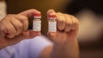 Uma enfermeira segura dois frascos da vacina AstraZeneca Covid-19 (Bloomberg)
