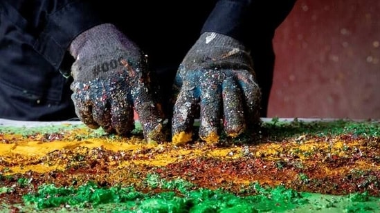 Filipino artist Gilbert Angeles works on a painting using expired paint and shredded plastic wrappers.(REUTERS)