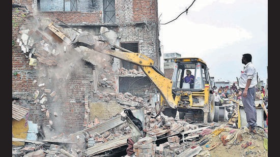 A JCB machine razing illegal structures near Buddha Nullah at Upkar Nagar. (HT Photo)