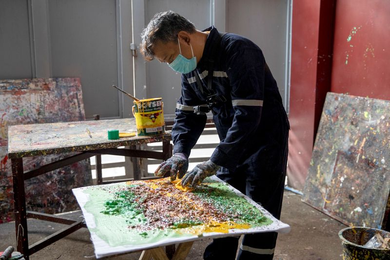 Filipino artist Gilbert Angeles incorporates expired paint and shredded plastic wrappers into a painting he is working on, at his studio in Plaridel, Bulacan province, Philippines. (REUTERS)